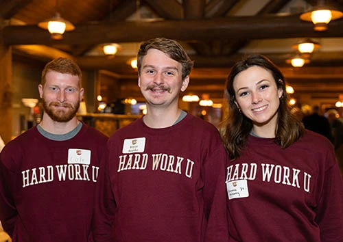 Three students wearing Hard Work U sweatshirts